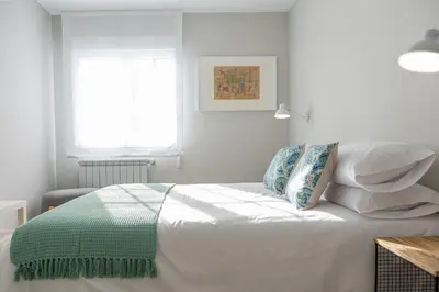 a bedroom with a bed with white sheets and pillows at Apartamento de diseño centrico con terraza espectacular in Santiago de Compostela