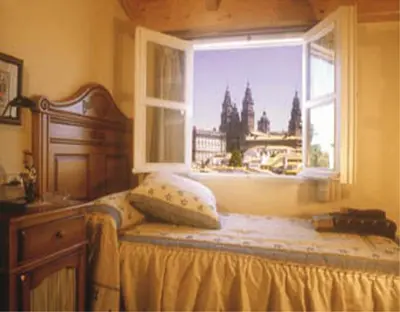 a bedroom with a bed and a window with a view at Hostal Alfonso in Santiago de Compostela