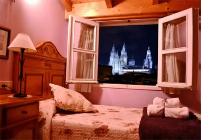a bedroom with a bed and a window with a castle at Hostal Alfonso in Santiago de Compostela