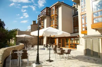 a patio with a table and chairs and an umbrella at Hotel Vila do Val in O Valadouro