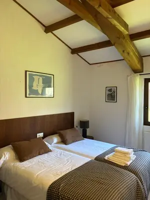 two beds in a bedroom with wooden ceilings at Casas do Campo in Monfero