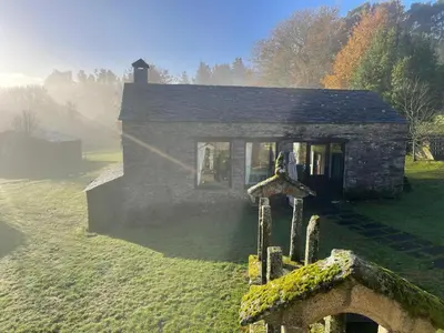 a small stone house with a cross in front of it at Casas do Campo in Monfero