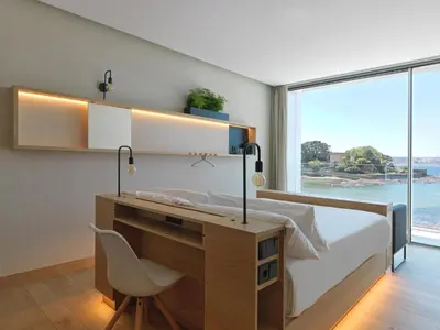 a bedroom with a bed with a desk and a window at Noa Boutique Hotel in Santa Cruz de Oleiros