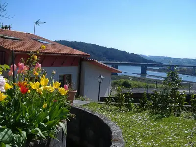 a house with flowers and a bridge in the background at CHALT EN MIÑO CON VISTAS AL MAR in A Coruña