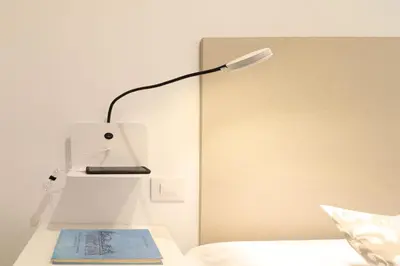 a desk with a lamp and a book on a bed at Estación de tren by Como en Casa in Santiago de Compostela