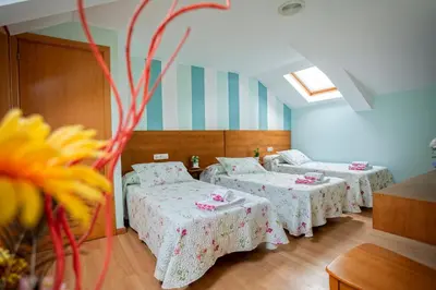a room with three beds and tables in it at CASA CINES in Lugo