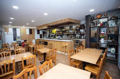 a restaurant with wooden tables and chairs and a bar at CASA CINES in Lugo