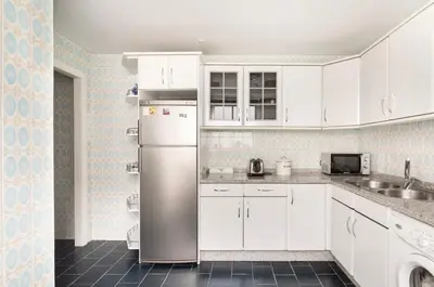 a kitchen with white cabinets and a stainless steel refrigerator at Apartamento en el centro de Ourense in Ourense