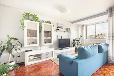 a living room with a blue couch and a tv at Apartamento en el centro de Ourense in Ourense