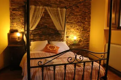 a bedroom with a black bed with a stone wall at Casa Rural Norita - Adults only in Lourenzá
