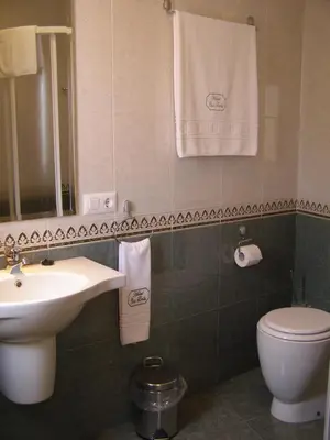 a bathroom with a sink and a toilet and towels at Hotel Casa Benilde in Palas de Rei