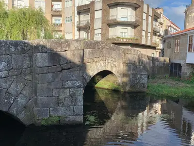 an old stone bridge over a river in a city at Home Sweet Home in Caldas de Reis