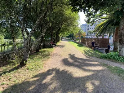 a dirt road with trees and people sitting on benches at Home Sweet Home in Caldas de Reis