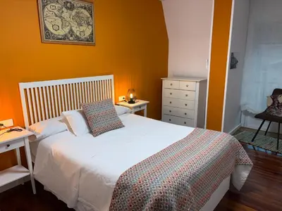 a bedroom with a white bed and orange walls at Home Sweet Home in Caldas de Reis