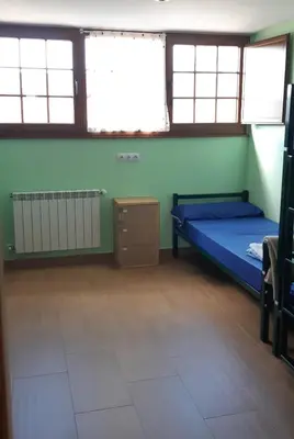 a bedroom with a bed and two windows at Albergue la escuela in La Laguna