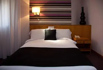 a bedroom with a white bed with a black pillow at Hotel Palacio de Cristal in Burela de Cabo