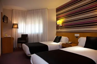 a hotel room with two beds and a chair at Hotel Palacio de Cristal in Burela de Cabo