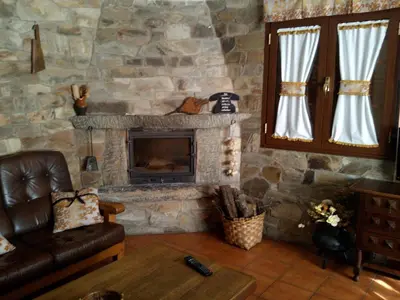 a living room with a couch and a stone fireplace at Casa Rural Las Nieves in San Ciprián