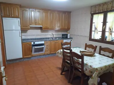a kitchen with a table and a white refrigerator at Casa Rural Las Nieves in San Ciprián