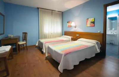 two beds in a room with blue walls and a desk at Hotel TERRANOVA in Oza dos Ríos