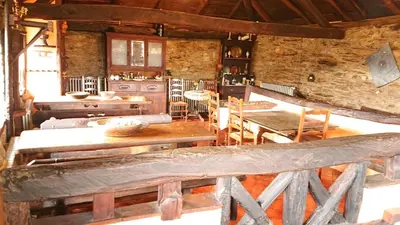 a kitchen with wooden tables and chairs in a room at Casa O´Crego in San Román