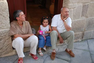 two adults and a little girl sitting on a wall at Hotel O Portelo Rural in Allariz