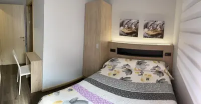 a small bedroom with a bed and two pictures on the wall at Pensión A Carballeira in Villalba