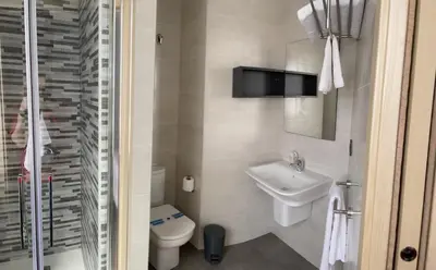 a bathroom with a sink and a toilet and a tv at Pensión A Carballeira in Villalba
