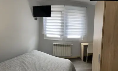 a bedroom with a bed and a window with blinds at Pensión A Carballeira in Villalba