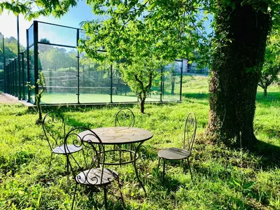 a table and chairs in a field with a tennis court at Finca BRIABÍ in La Cañiza