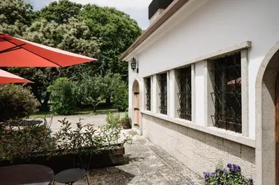 a patio with tables and an umbrella next to a building at Finca BRIABÍ in La Cañiza