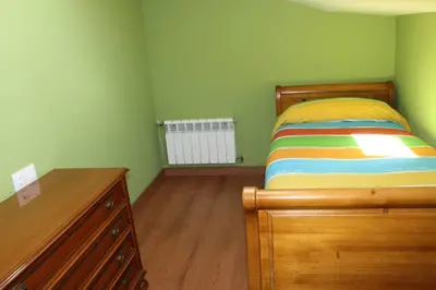 a bedroom with a bed and a dresser and a radiator at Casa Dana in Santiago de Compostela