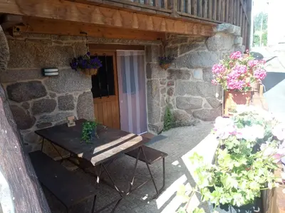 a picnic table in front of a stone building with flowers at Apartamento do Xurés in Maus de Salas