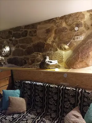 a room with a stone wall and a couch with pillows at Apartamento do Xurés in Maus de Salas