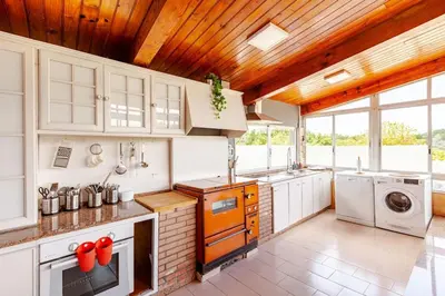 a kitchen with white cabinets and a wooden ceiling at Casa Mosteiro in Bribes