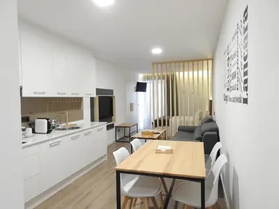 a kitchen and living room with a table and chairs at Galerías 16 Viviendas Turísticas in Lugo