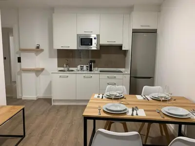 a kitchen with a wooden table and white cabinets at Galerías 16 Viviendas Turísticas in Lugo