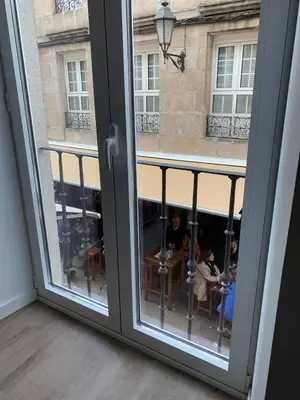 an open window with people sitting at tables outside at Galerías 16 Viviendas Turísticas in Lugo