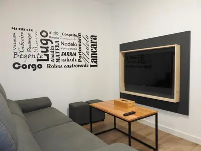 a living room with a couch and a table with a tv at Galerías 16 Viviendas Turísticas in Lugo