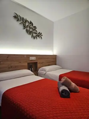 a room with two beds with red and white sheets at PENSION ROSELLA in O Pedrouzo