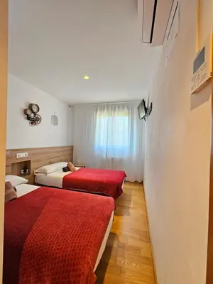 two beds in a hotel room with red blankets at PENSION ROSELLA in O Pedrouzo
