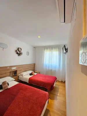 a hotel room with two beds with red sheets at PENSION ROSELLA in O Pedrouzo