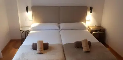 a bedroom with a large white bed with two towels at PENSION ROSELLA in O Pedrouzo