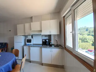 a kitchen with white cabinets and a large window at Estrella Do Camiño in Caldas de Reis