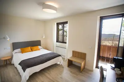 a bedroom with a bed and a large window at Villa Lucerna Sports & Hotel Resort in Vigo de Sanabria