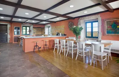 a kitchen with orange walls and a table and chairs at Casa Vistaboa Ribeira Sacra in Chantada