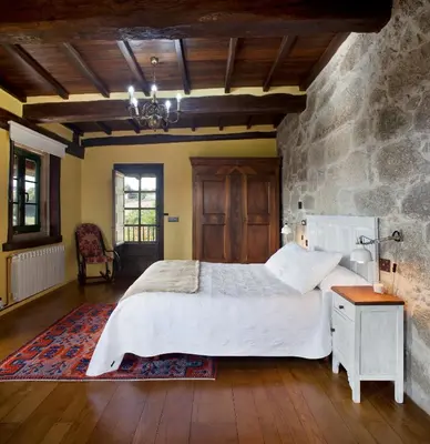 a bedroom with a large bed and a stone wall at Casa Vistaboa Ribeira Sacra in Chantada