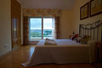 a bedroom with a bed and a large window at CHALET CON PISCINA EN MIÑO-Perbes in Miño