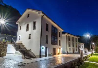 a large white building with stairs next to a building at Apartamentos Buenavista Tineo in Tineo