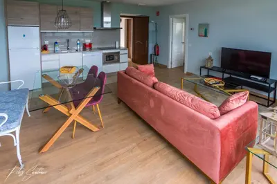 a living room with a red couch and a kitchen at Apartamentos Buenavista Tineo in Tineo